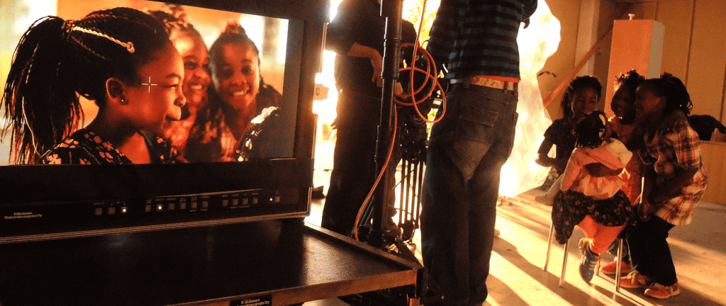 Three girls smile on a video monitor