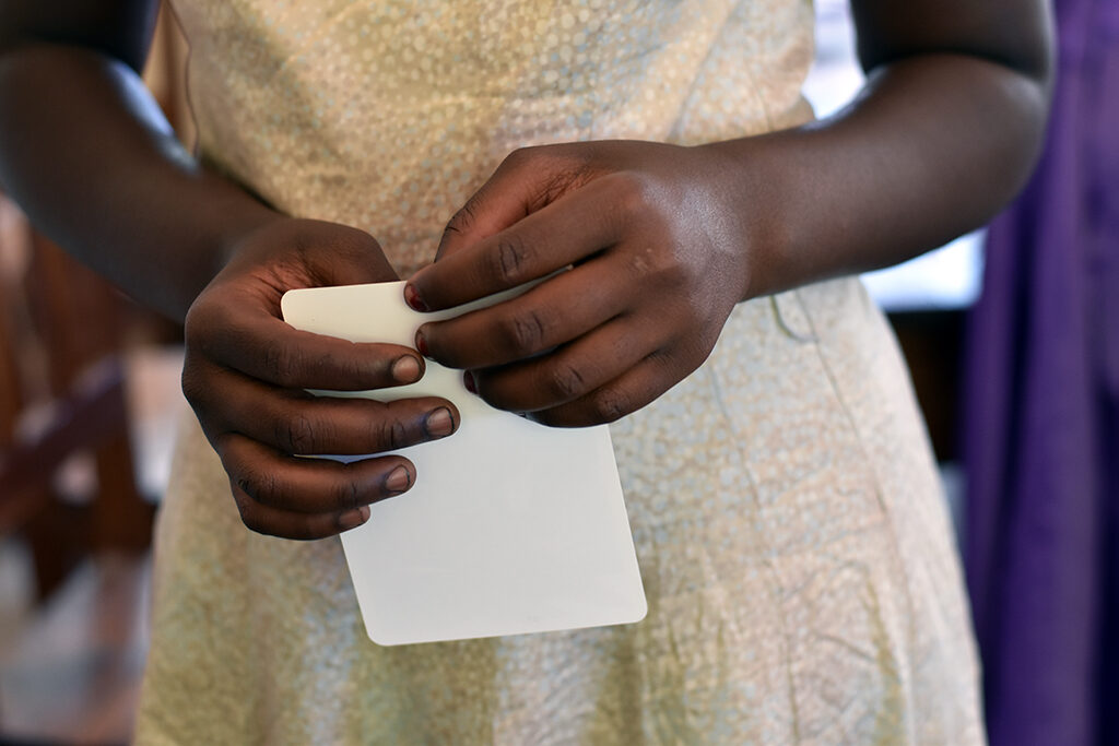 A young woman is holding a card in her hands. It is not visible what the card reads.